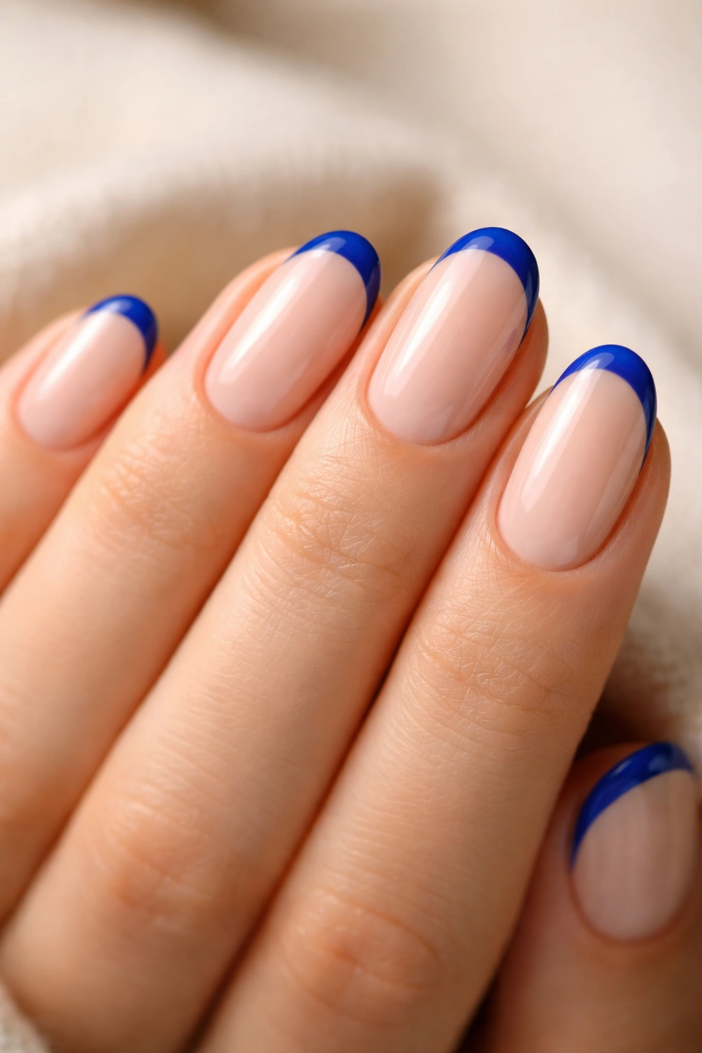 Close-up of short oval nails with cobalt blue tips on a translucent base