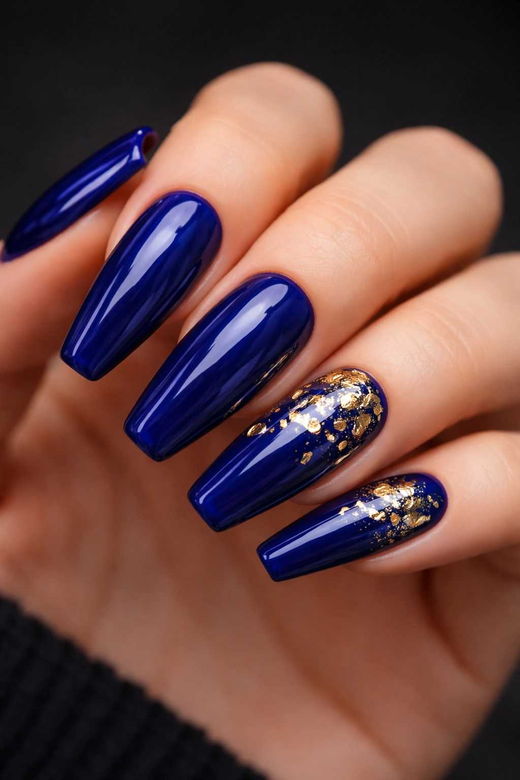 Deep cobalt nails with scattered gold foil flecks on a ballerina nail