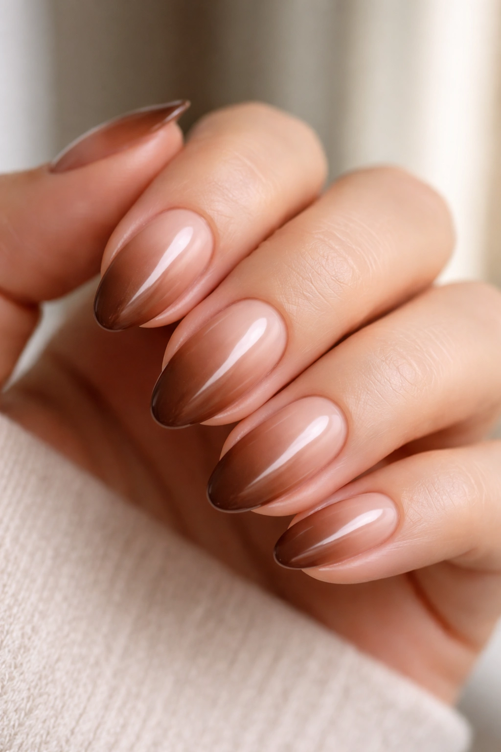 Close-up of cocoa ombré short almond nails fading to brown at tip
