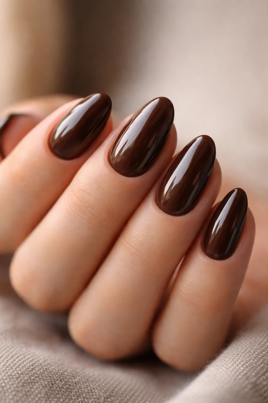 Close-up of coffee brown nails with a glossy dome finish on short almond nails