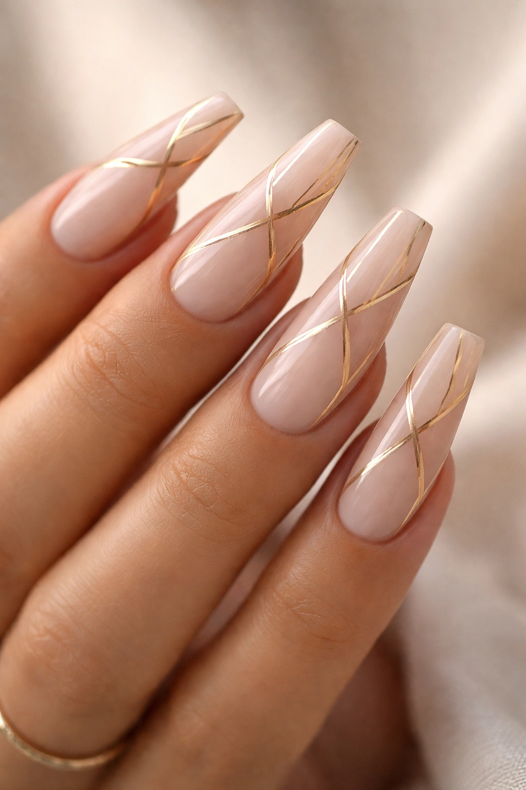 Close-up of coffin nails with nude base and gold geometric lines