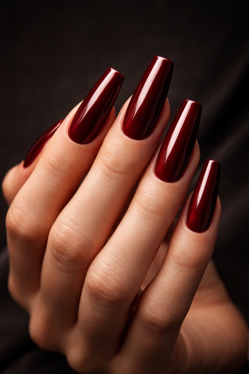 Close-up of coffin-shaped nails painted burgundy red on a hand
