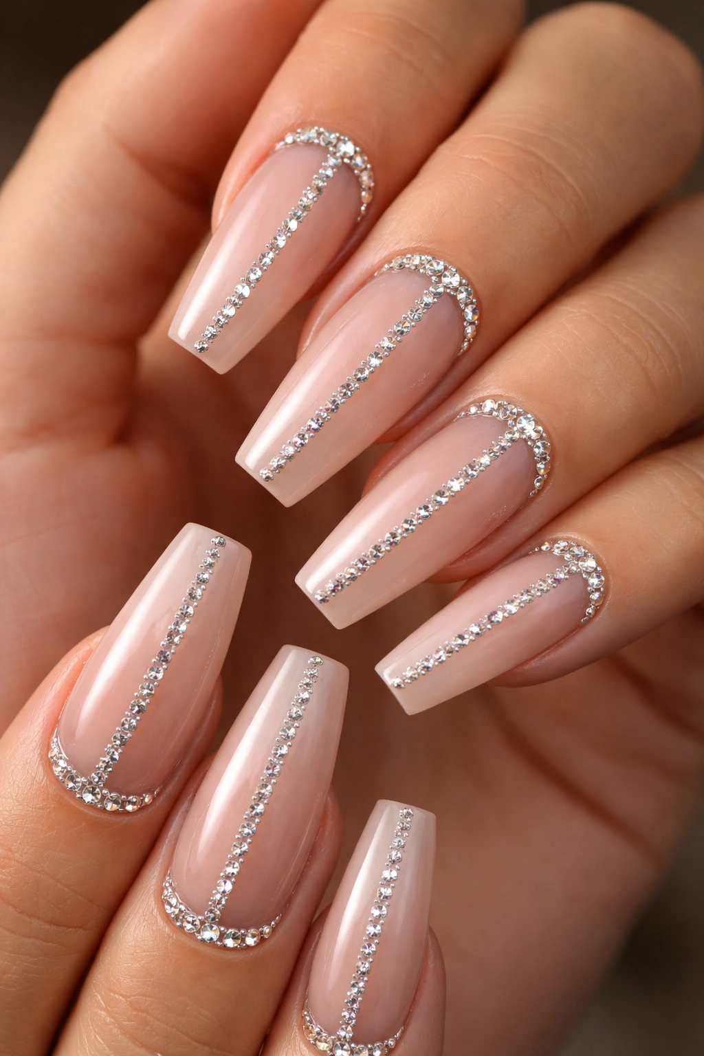 Close-up of coffin-shaped nails with a centerline of rhinestones on a nude base