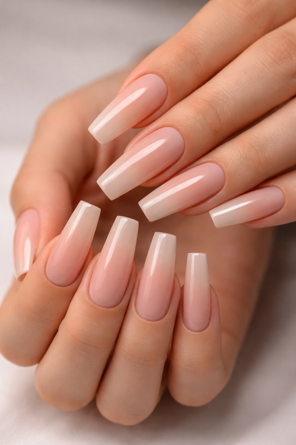 Close-up of coffin nails with squared tips on a hand in a neutral studio setting