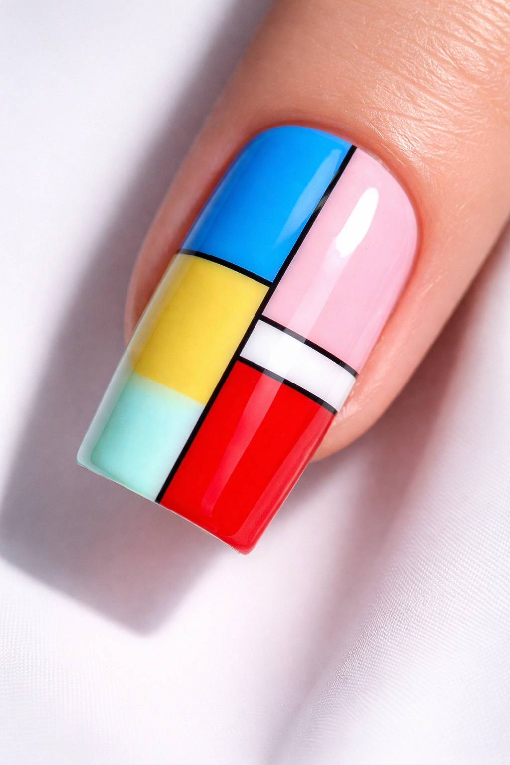 Close-up of a square nail with color-block design in pastel and primary colors