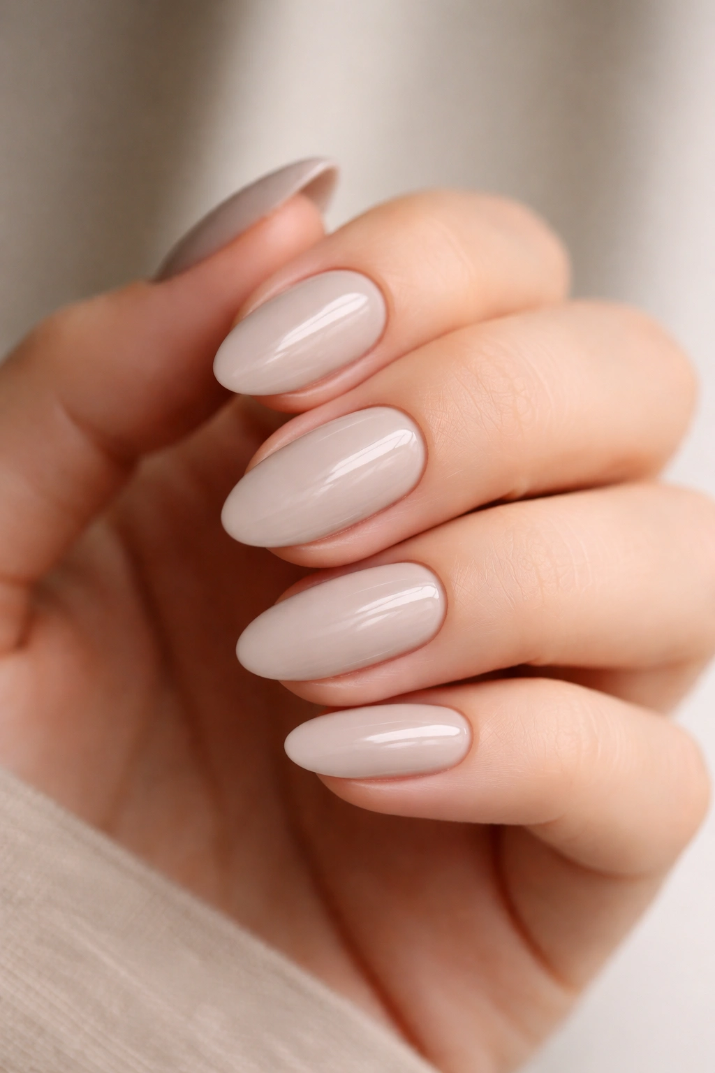 Close-up of short almond nails in cool beige greige with a crisp finish