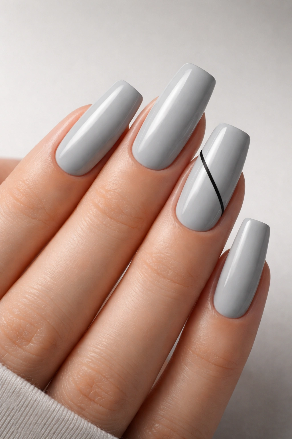 Close-up of long squoval nails in cool gray with a subtle geometric accent line