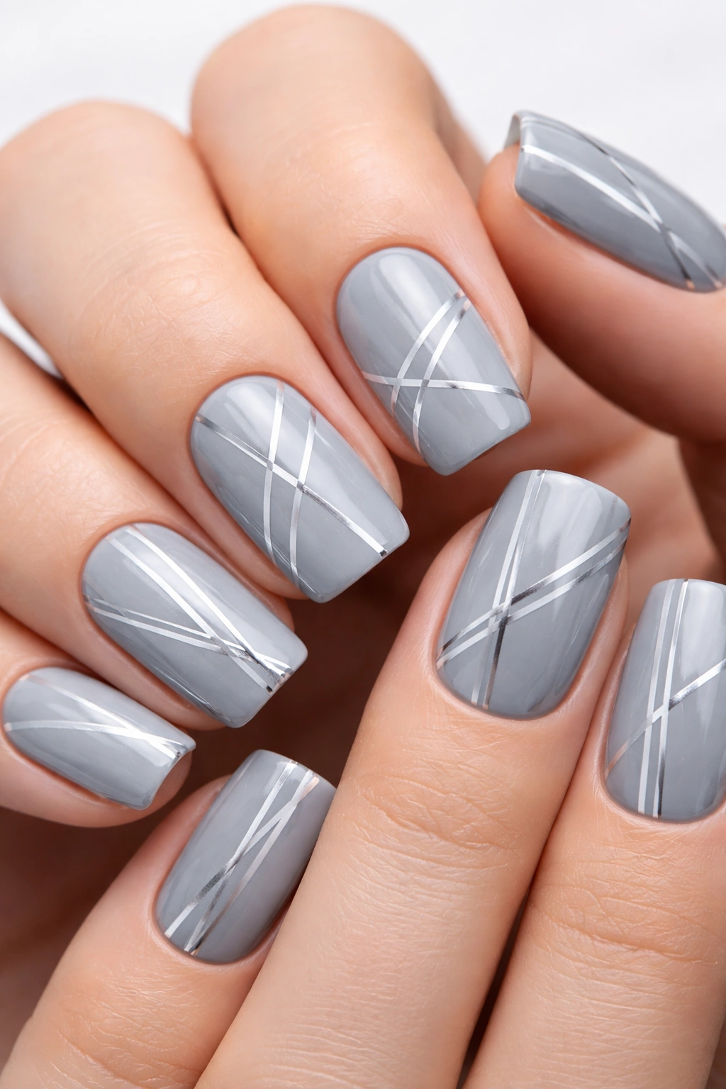Close-up of cool gray nails with silver geometric line patterns