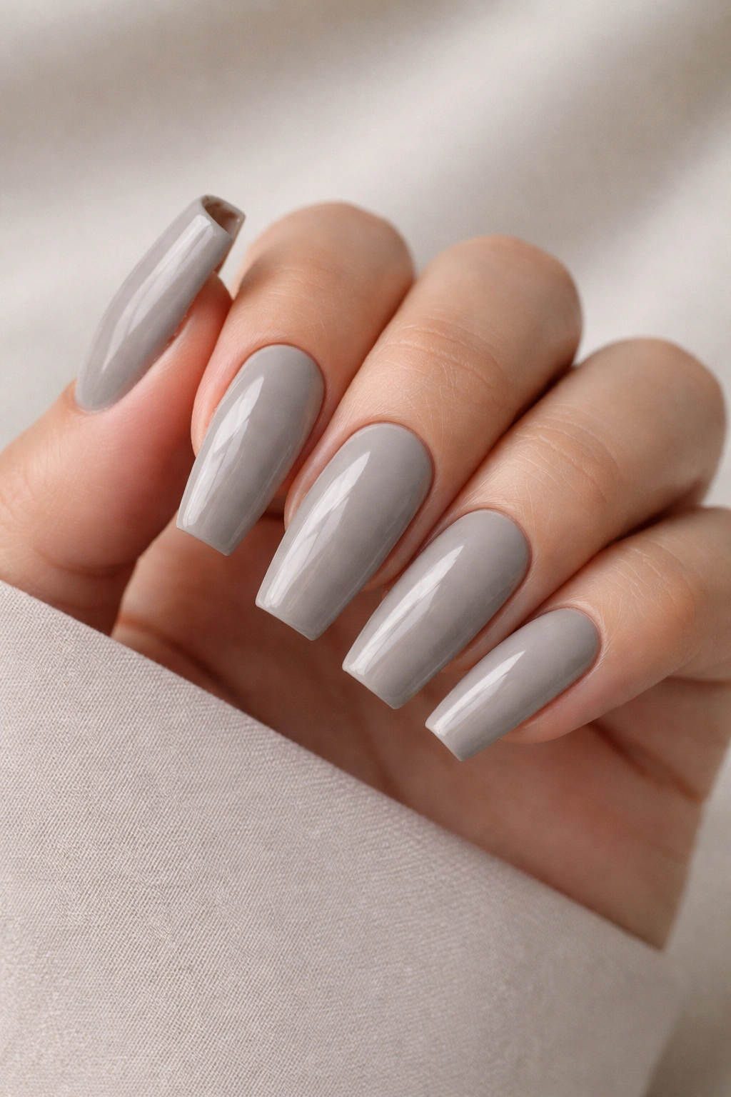 Close-up of medium coffin nails in cool gray nude greige shade against a neutral backdrop