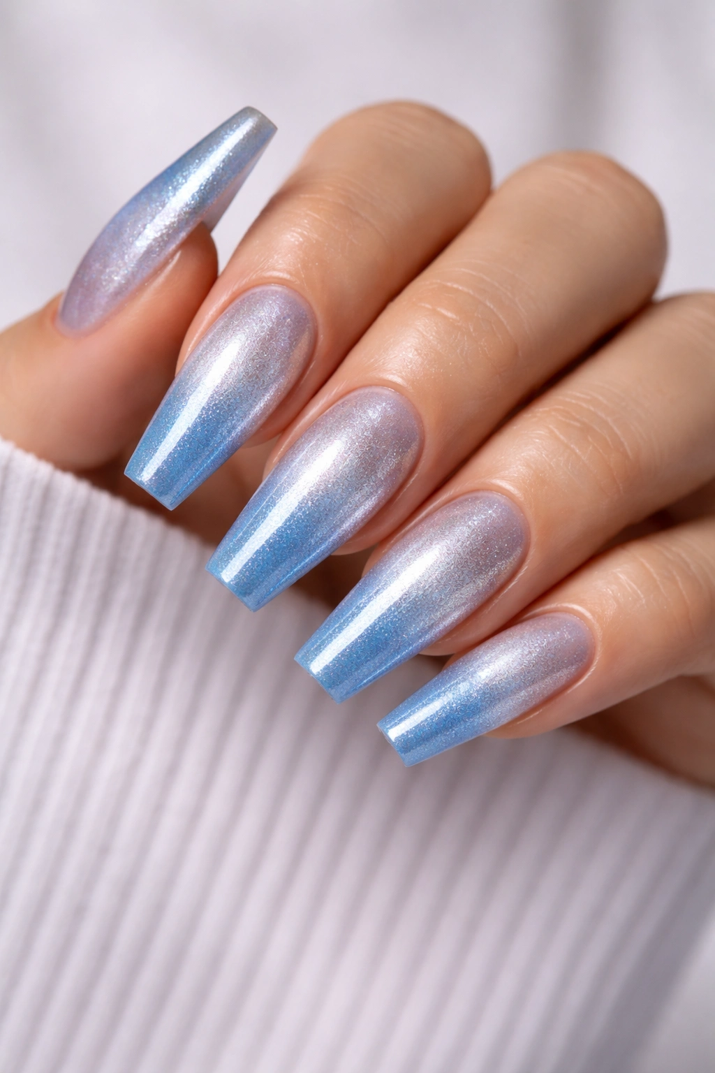 Close-up of cool-toned ombre coffin nails silver to blue gradient.