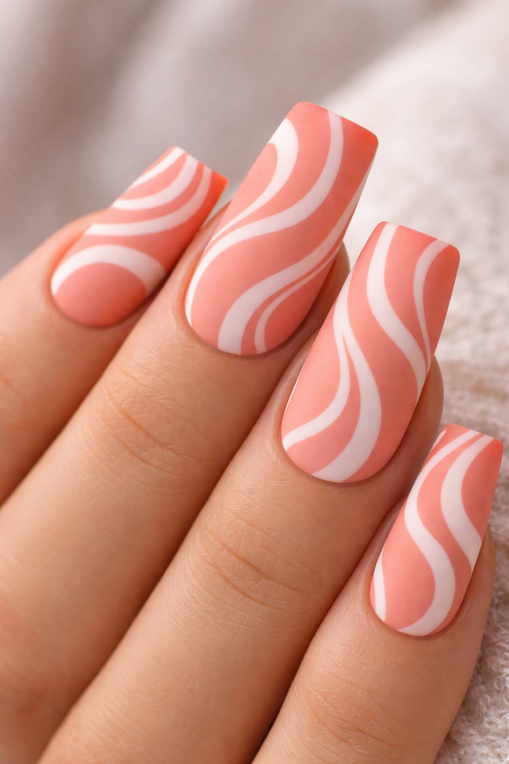 Coral nails with white swirl pattern and matte finish