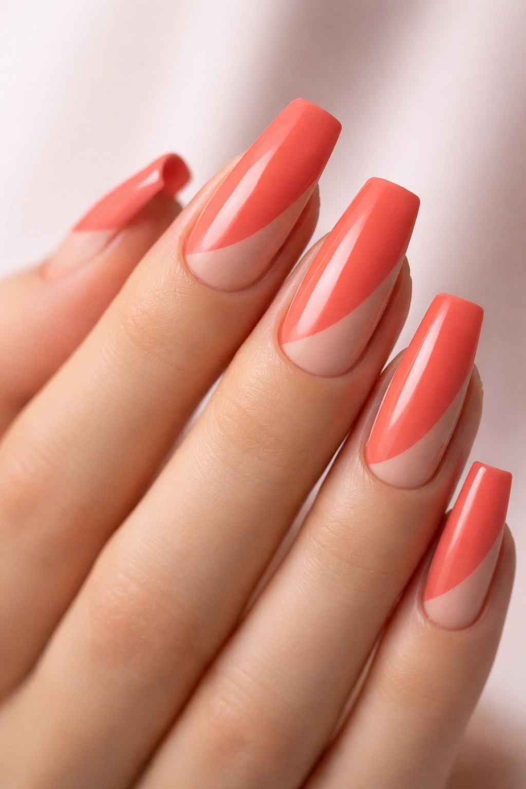 Close-up of coral nails with matte nude negative space on squoval shape