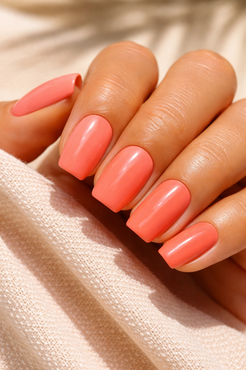 Close-up of coral nails against sun-kissed skin