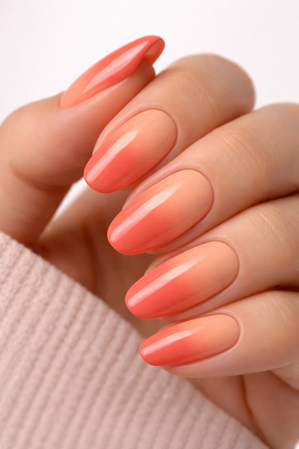Close-up of coral and peach colored nails in a two-tone manicure