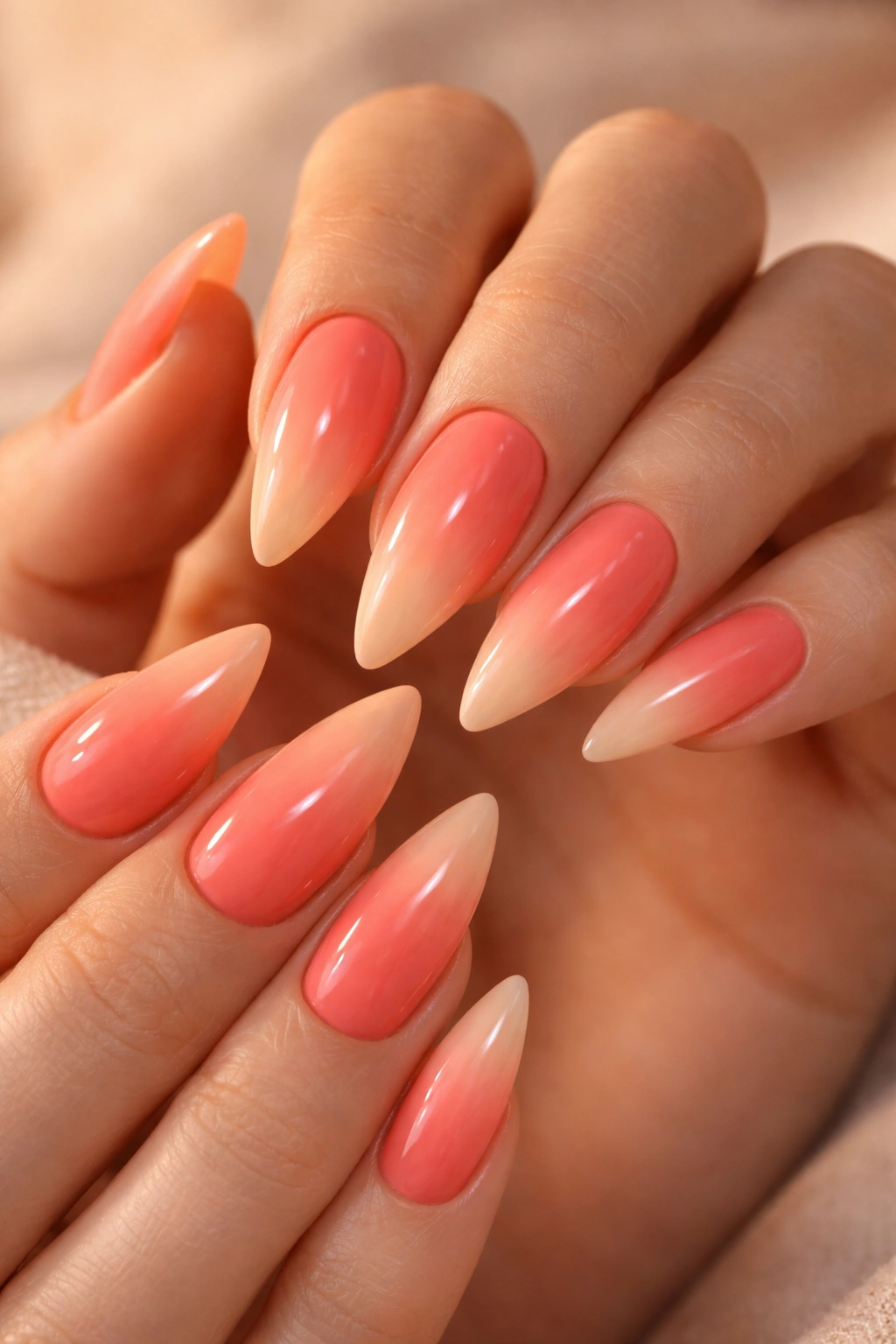 Close-up of medium stiletto nails with coral-to-peach ombre on hands