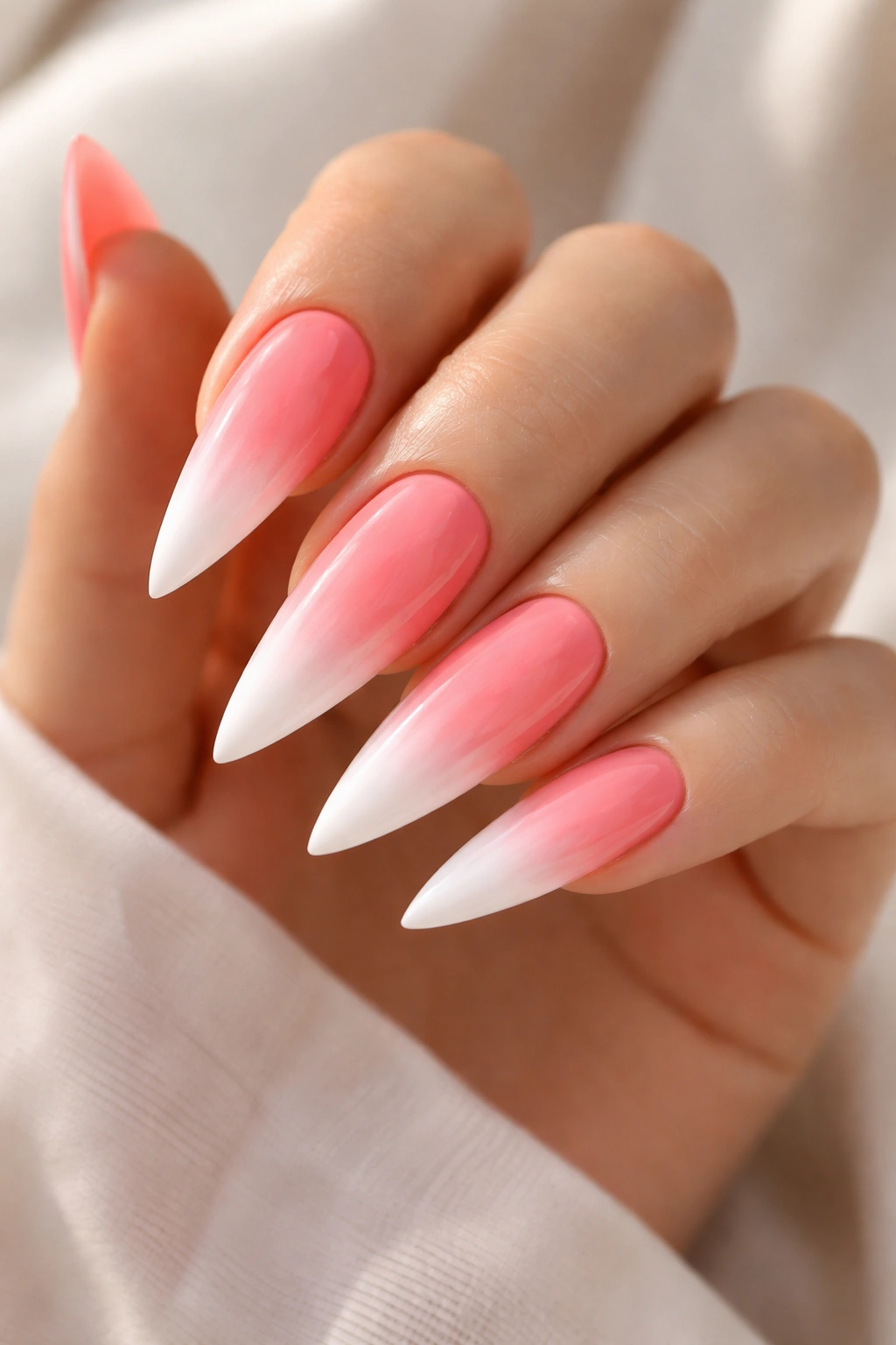 Close-up of coral pink stiletto nails with white ombre fade at the tips