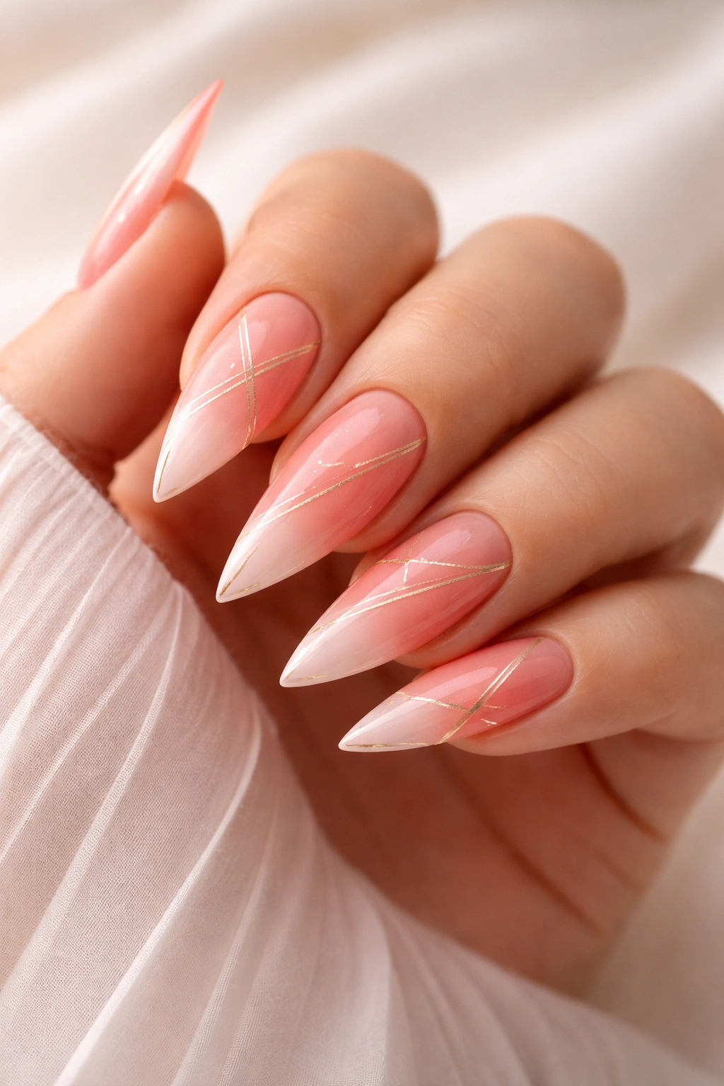 Stiletto nails with coral-to-pink ombre and geometric lines on a plain backdrop