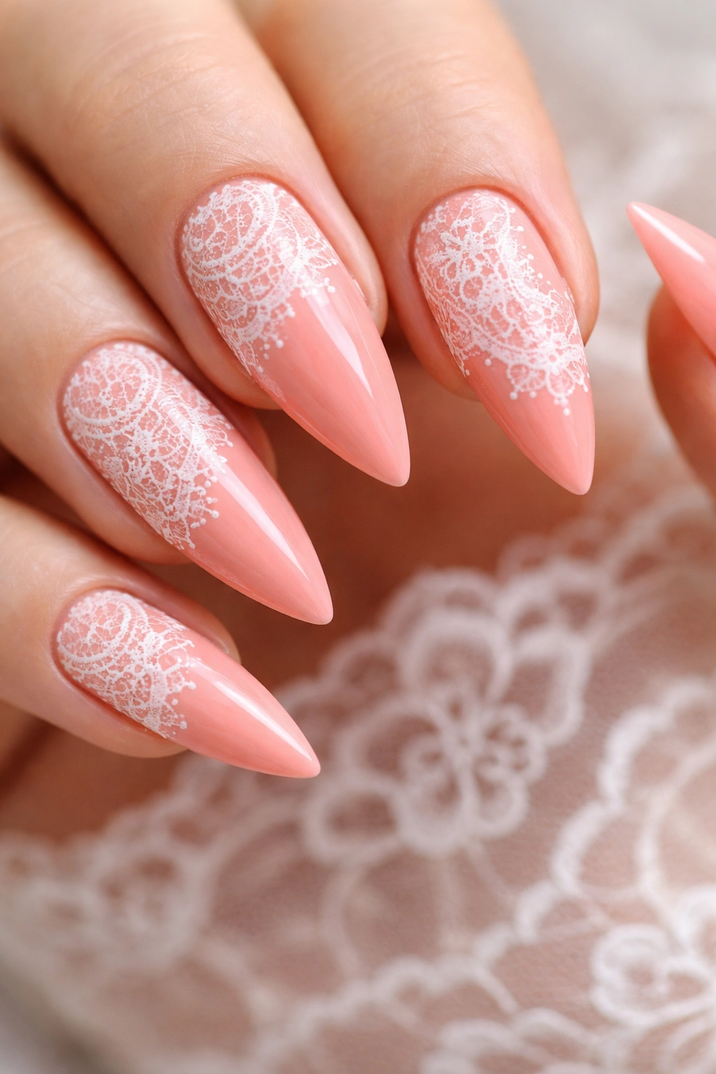 Close-up of coral-pink nails with white lace detail
