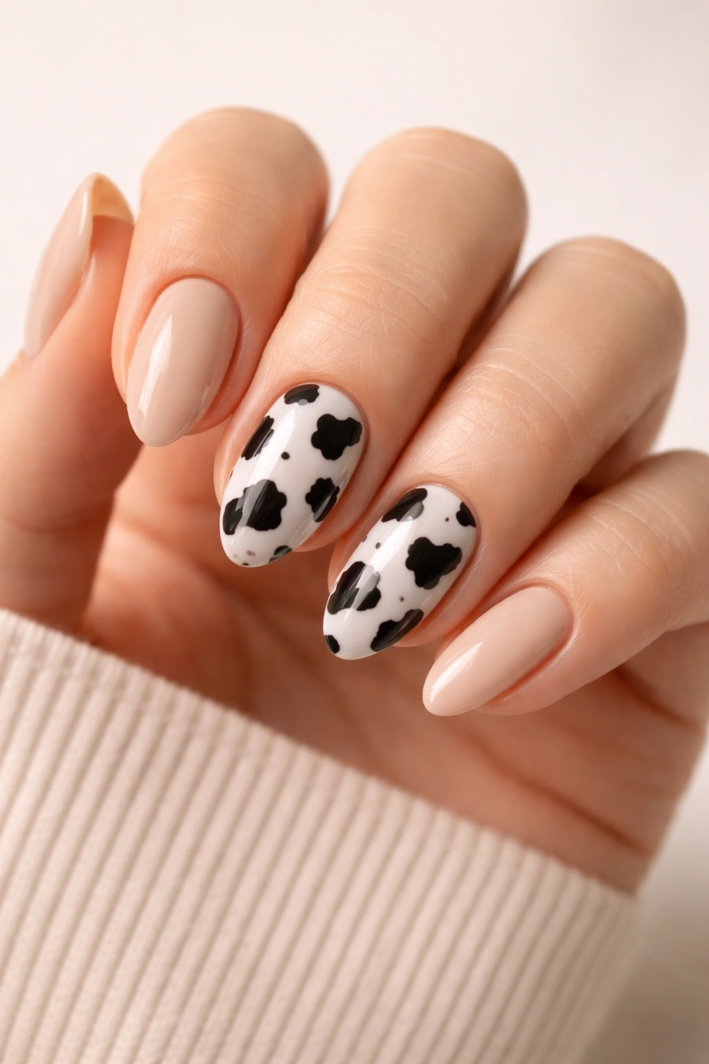 Close-up of short almond nails with cow print accents and solid neutral filler