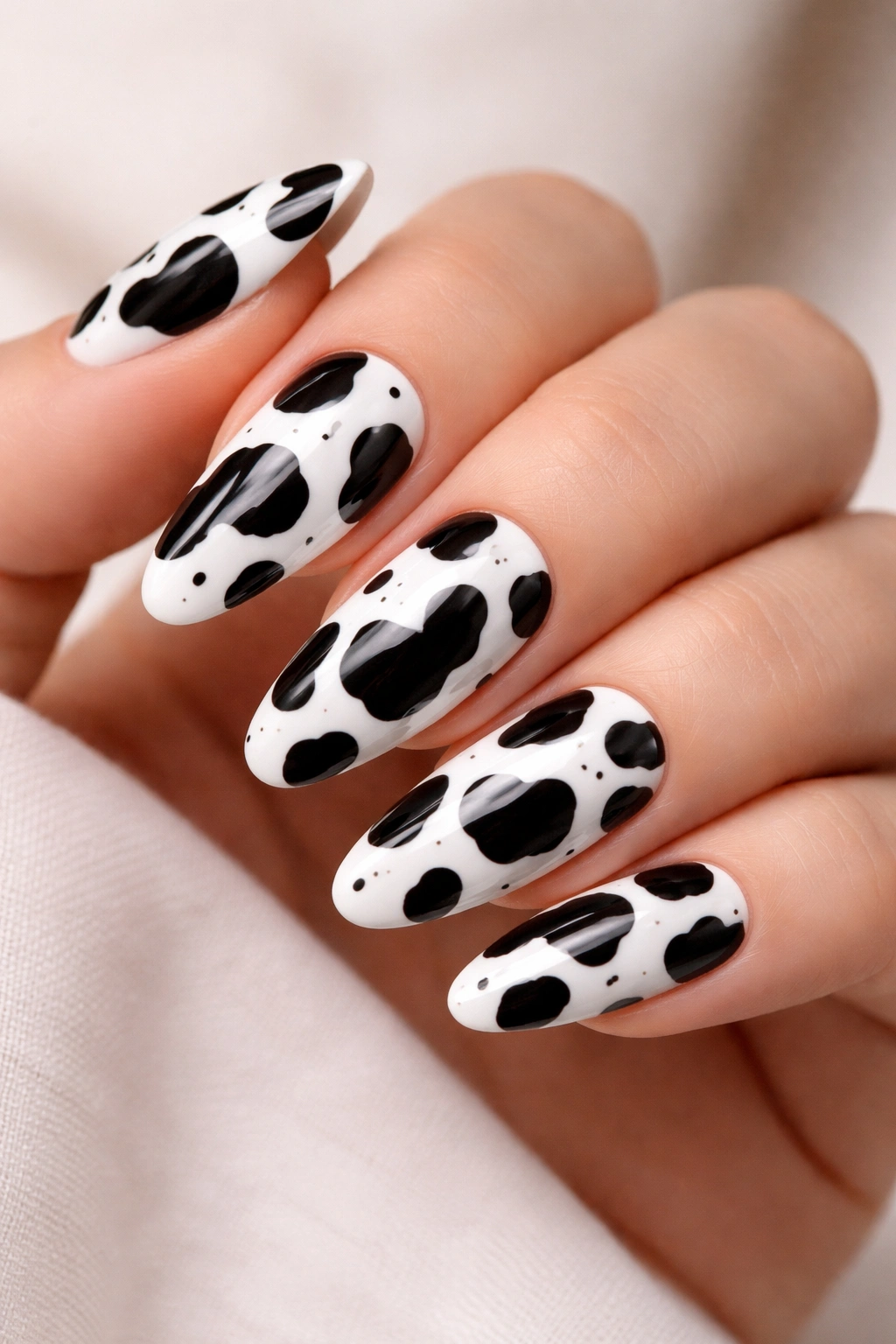 Close-up of classic black and white cow print nails on a hand