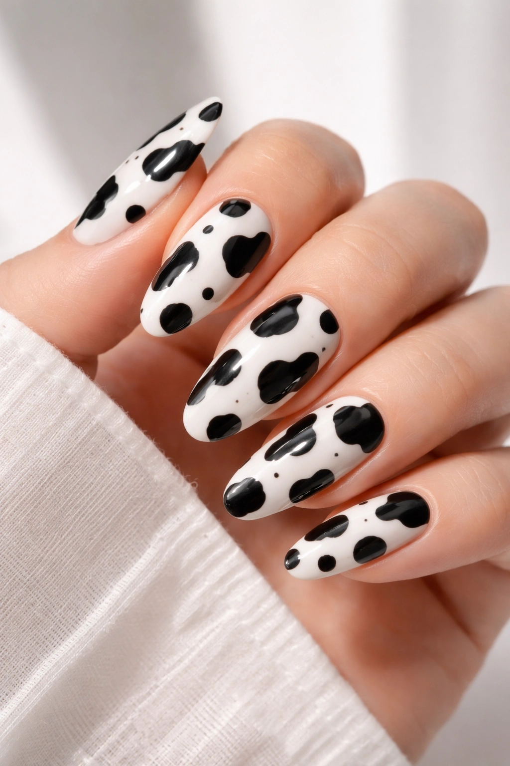 Close-up of black cow print nails on white or nude base.