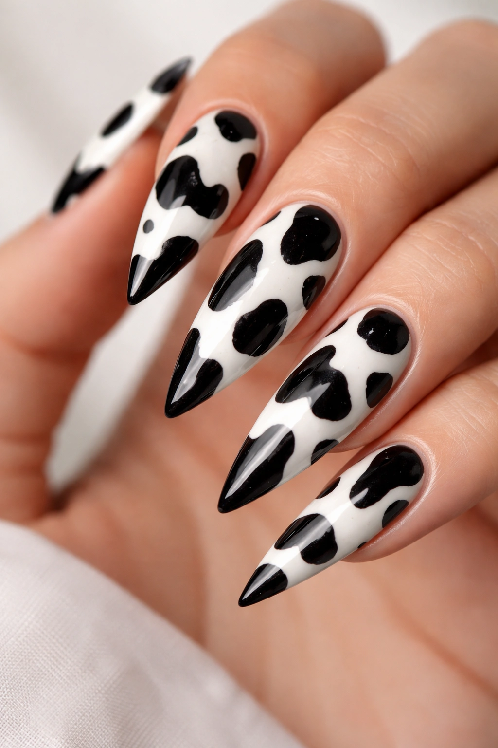 Close-up of classic black and white cow print stiletto nails with glossy finish