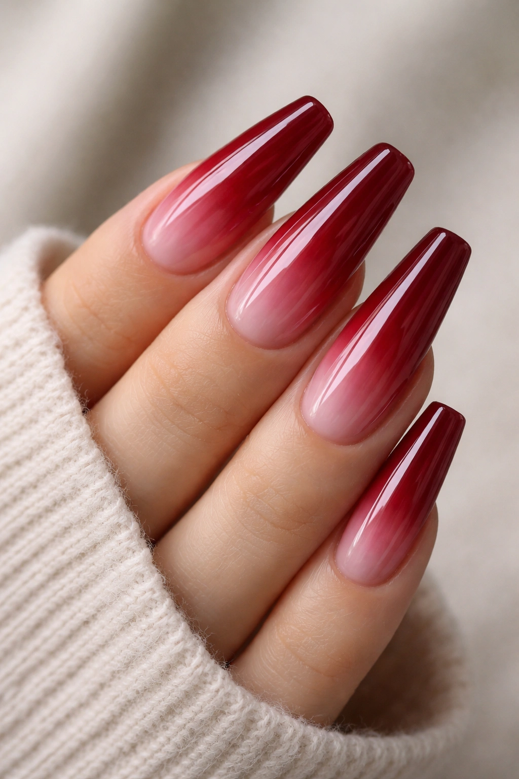 Close-up of tapered ballerina nails with cranberry red over a milky base.