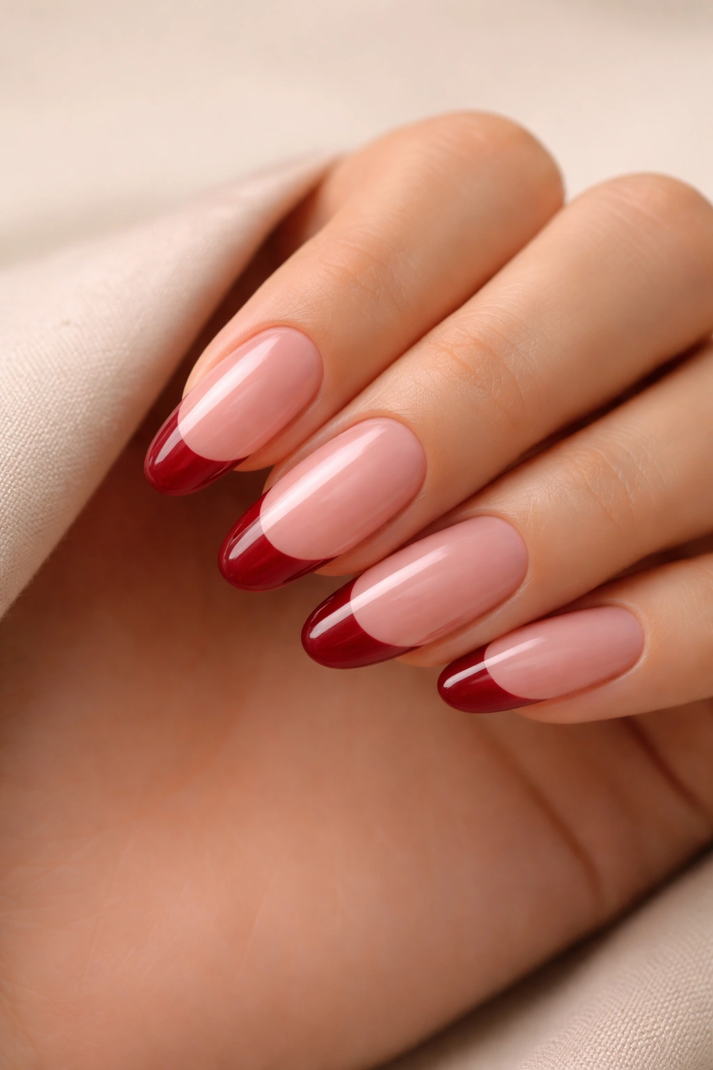 Close-up of long oval nails with sheer pink base and cranberry tips