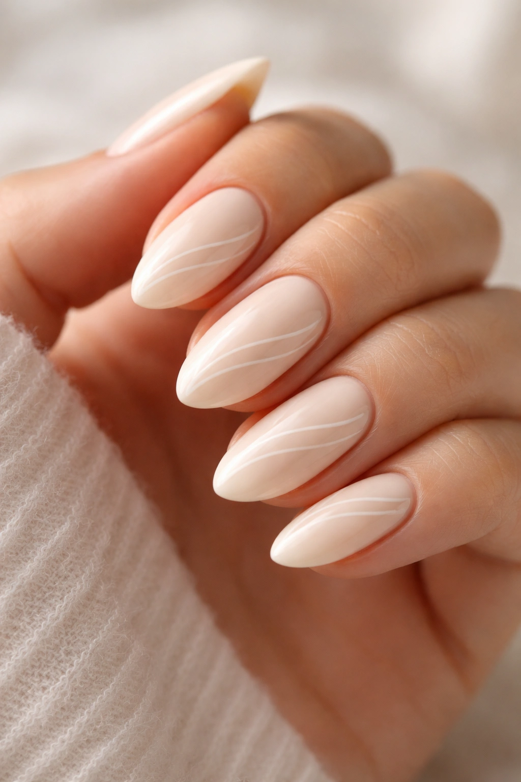 Short almond nails with delicate white swirls on cream base.