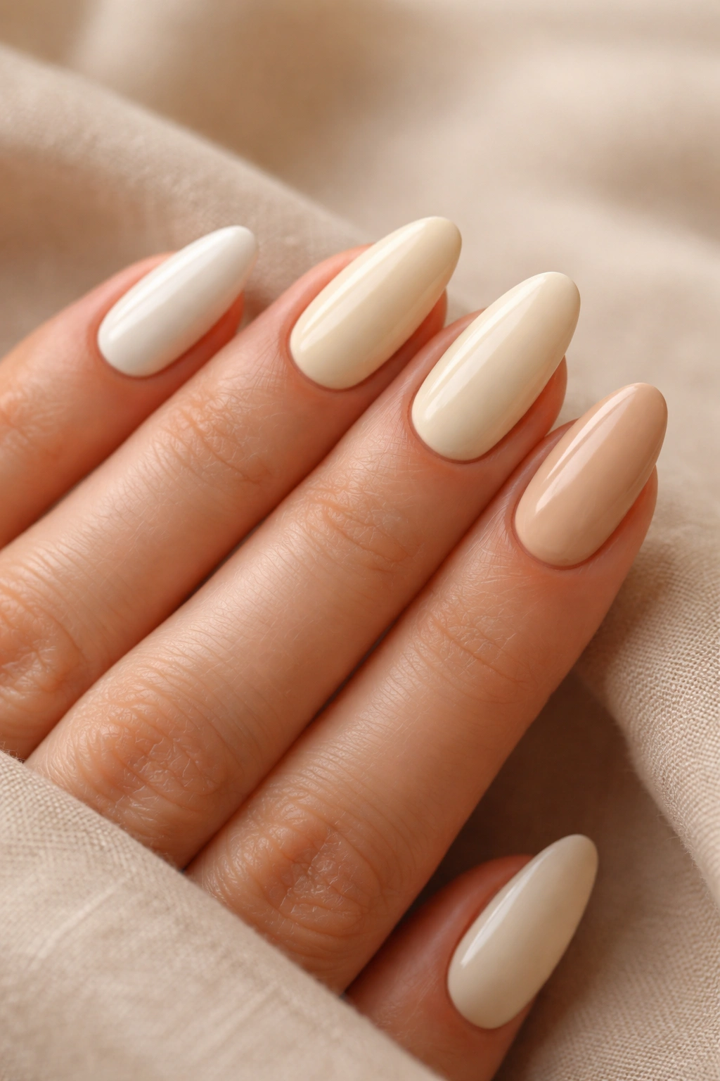 Hand showing multiple cream shade nails on a neutral background