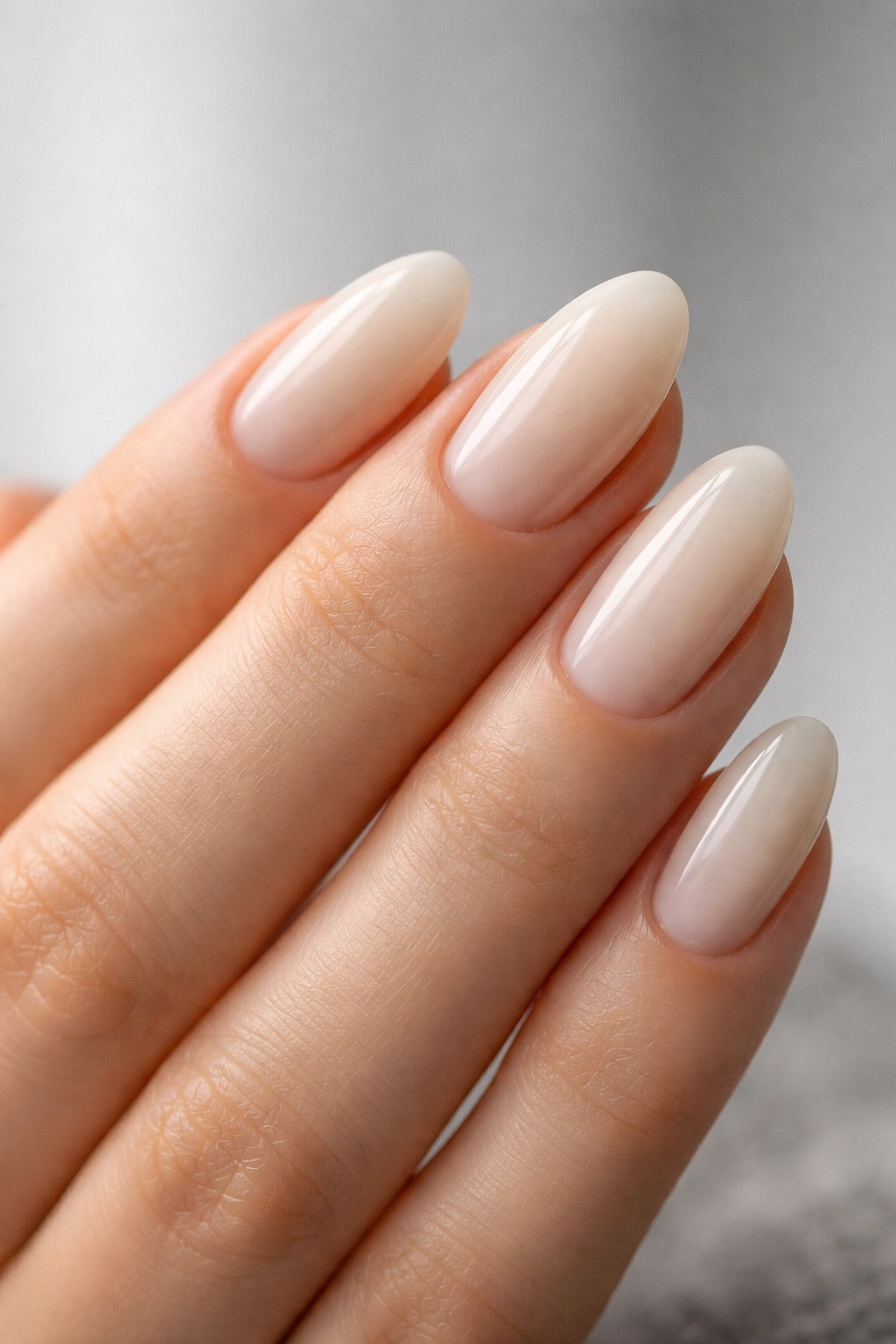 Close-up of creamy milky almond nails with translucent off-white polish on a short almond shape