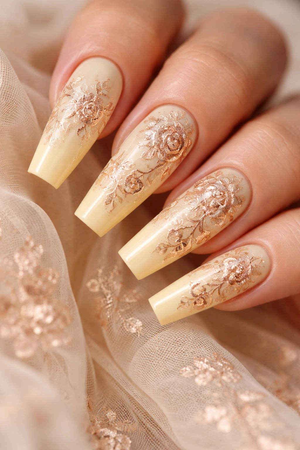 Close-up of creamy yellow coffin nails with rose gold floral stamping