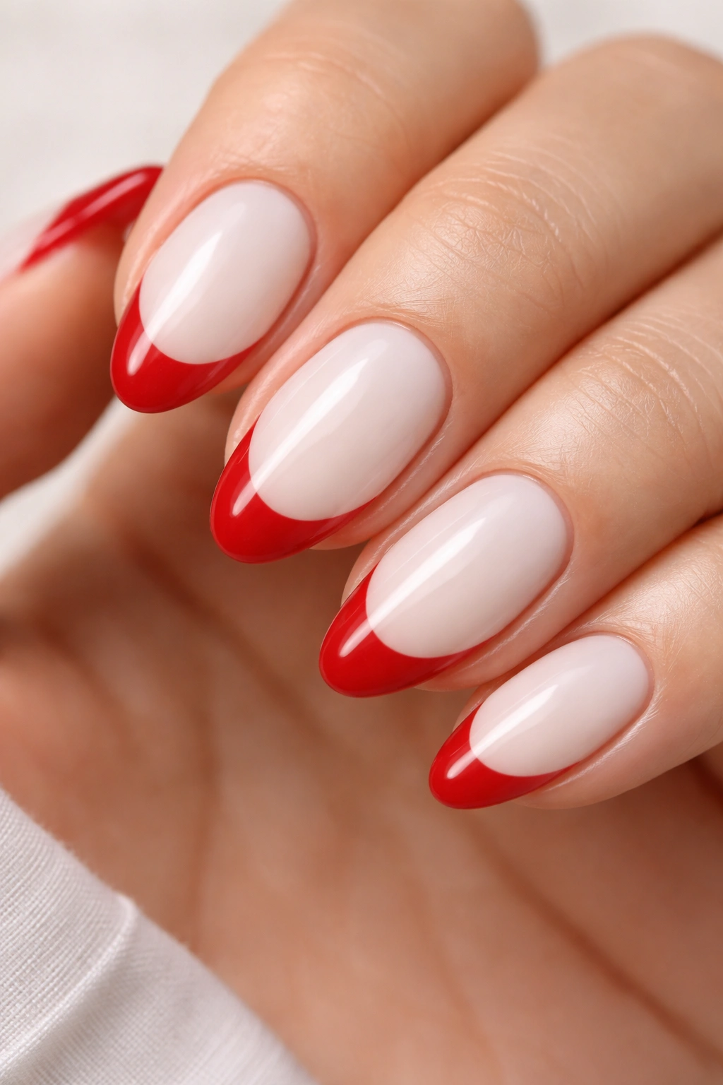 Close-up of short almond nails with milky white base and crimson tips in sharp contrast