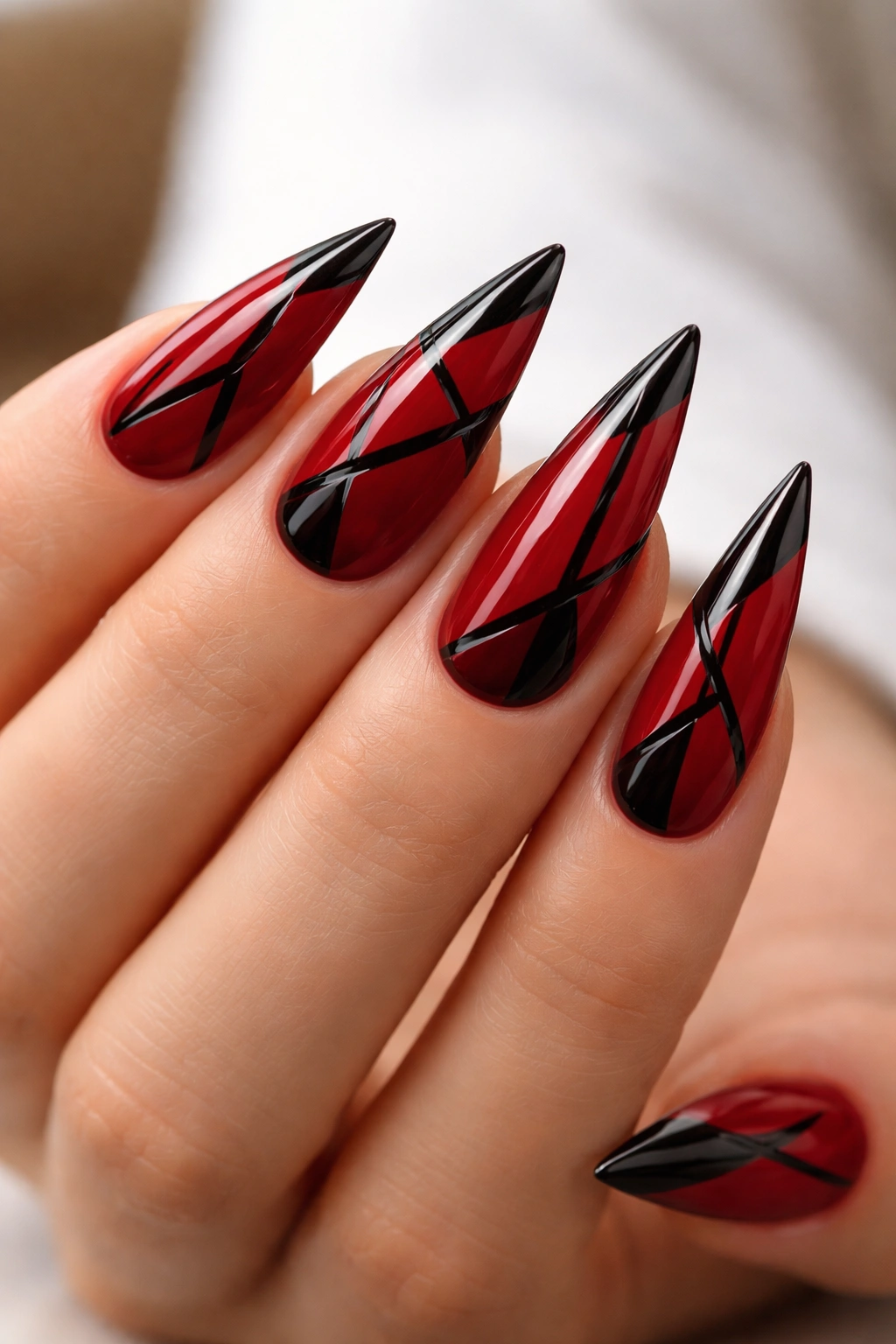 Crimson stiletto nails with black geometric patterns on medium length.