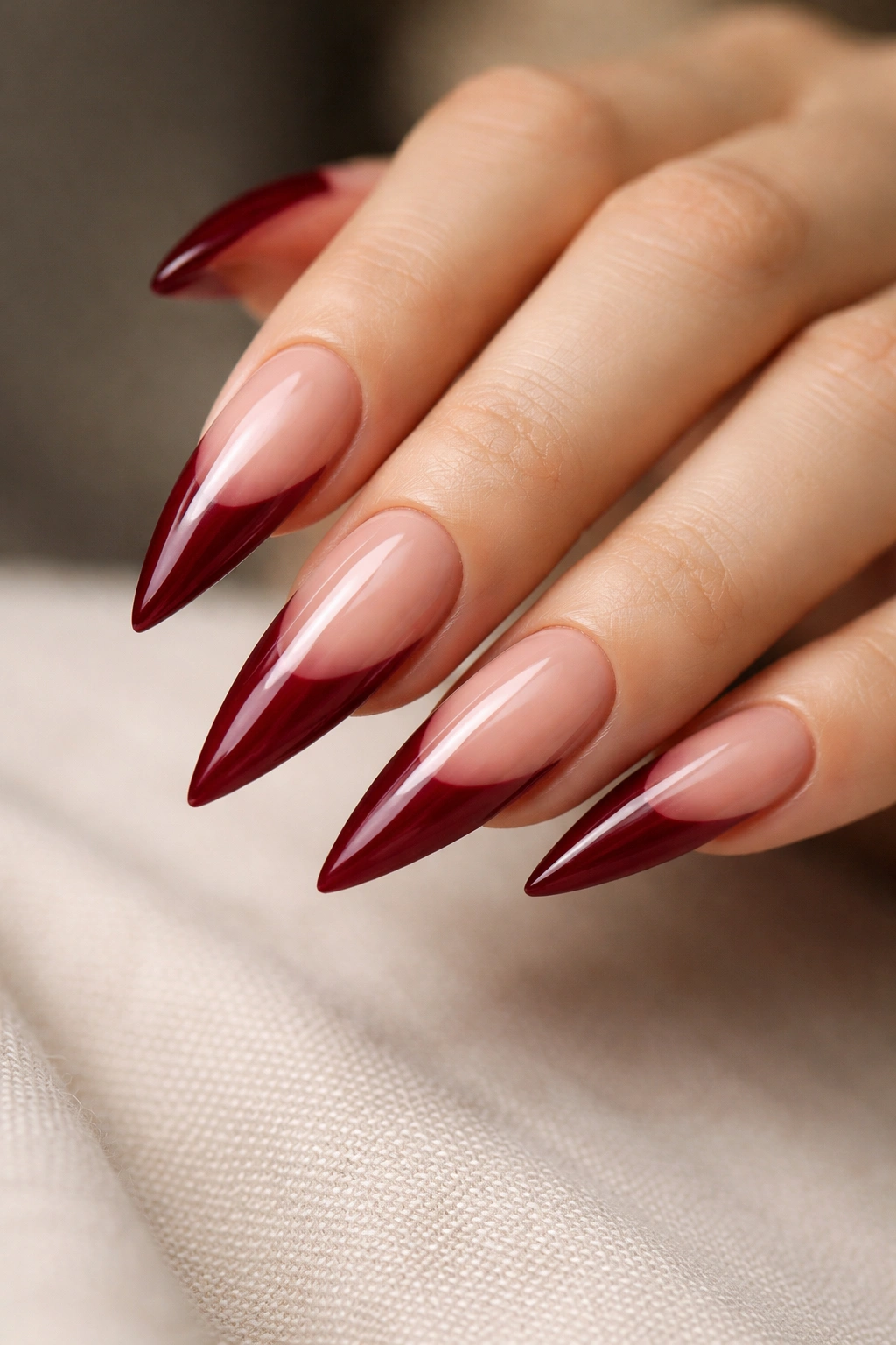 Close-up crimson nails with nude tips and elongated silhouette