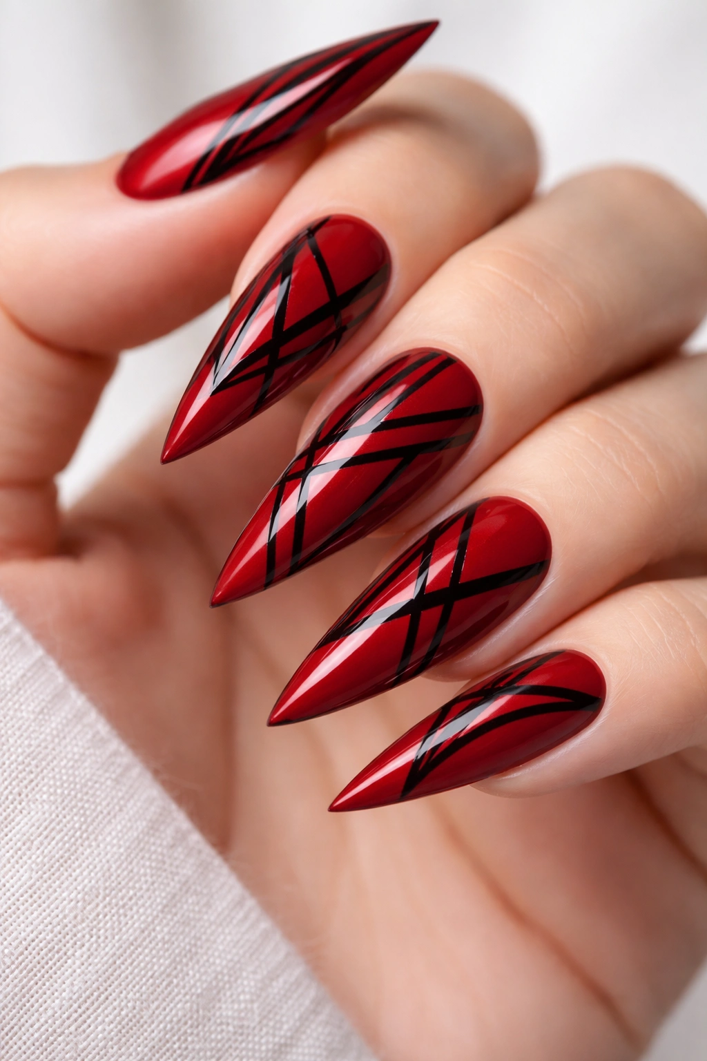 Crimson red stiletto nails with black geometric lines and sharp patterns.