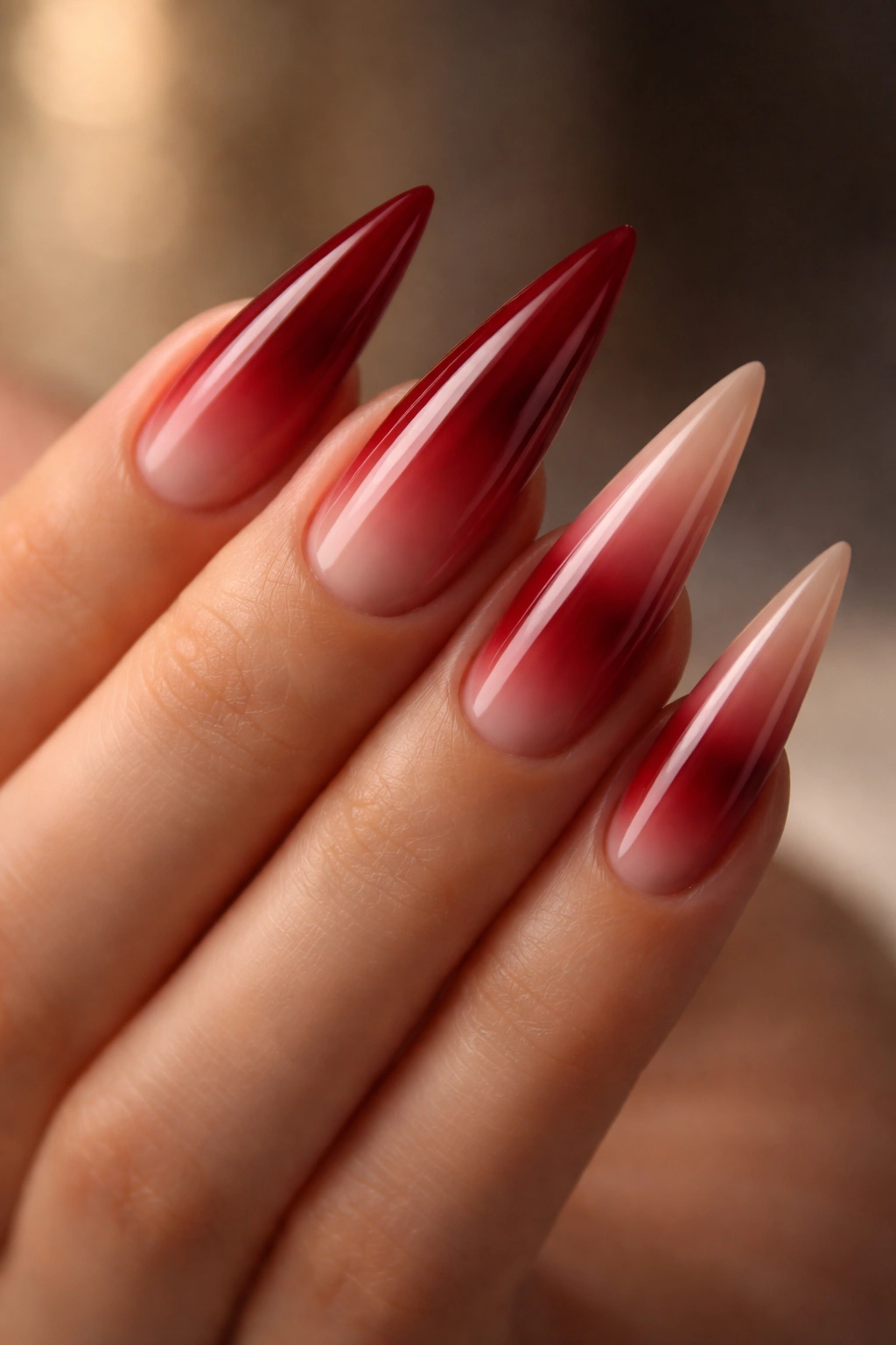Crimson red nails with gradient to nude on stiletto shape