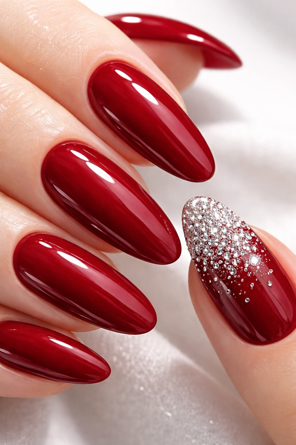 Crimson red nails with a micro rhinestone accent nail on one finger.