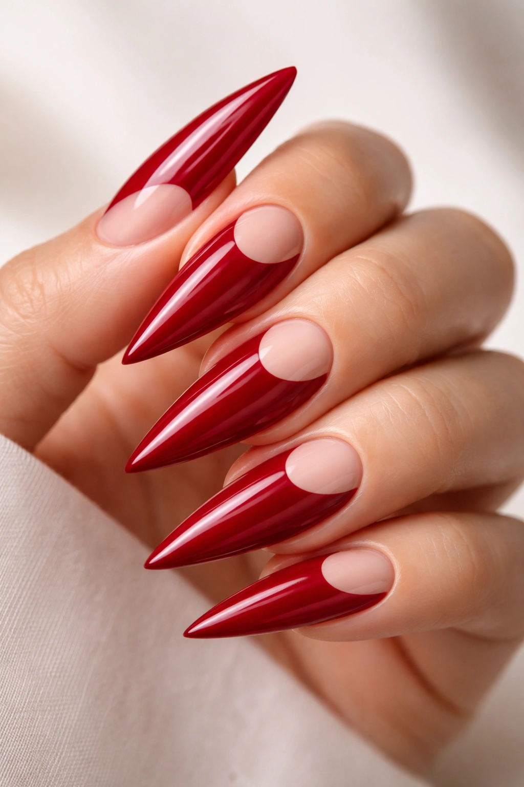 Crimson red stiletto nails with a curved negative-space moon design