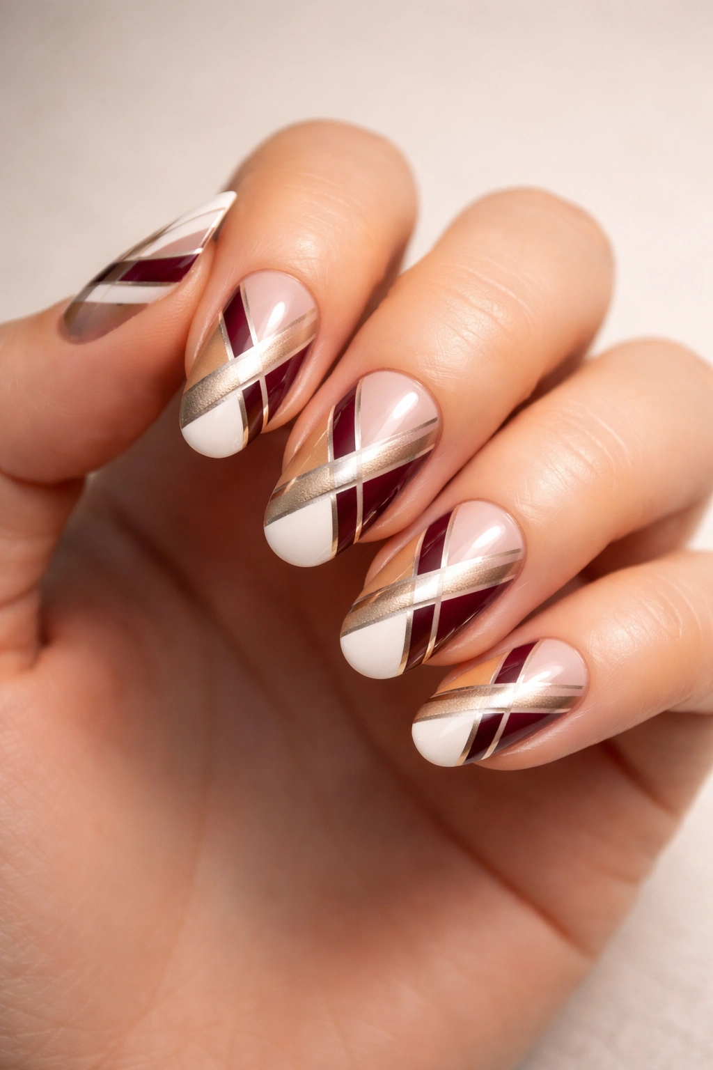 Close-up of nails with crisscross diagonal stripes in white gold burgundy