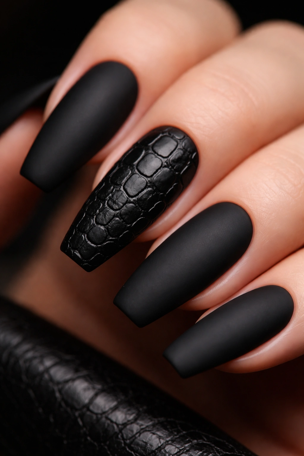Close-up of a matte black nail with a crocodile texture accent on a single nail