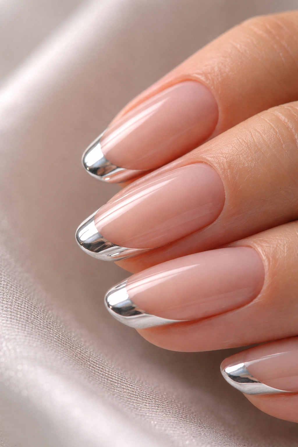 Close-up of a short oval nail with crystal chrome tip on sheer pink base showing glass-like shine