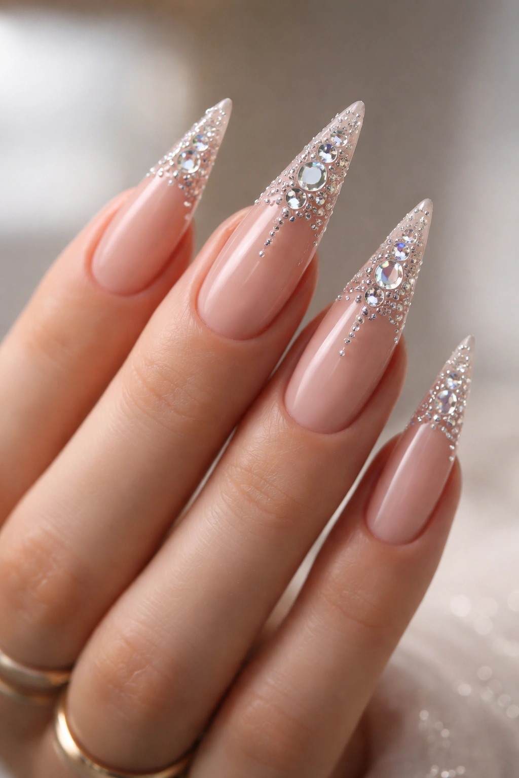 Nude stiletto nails with crystal accents along tips