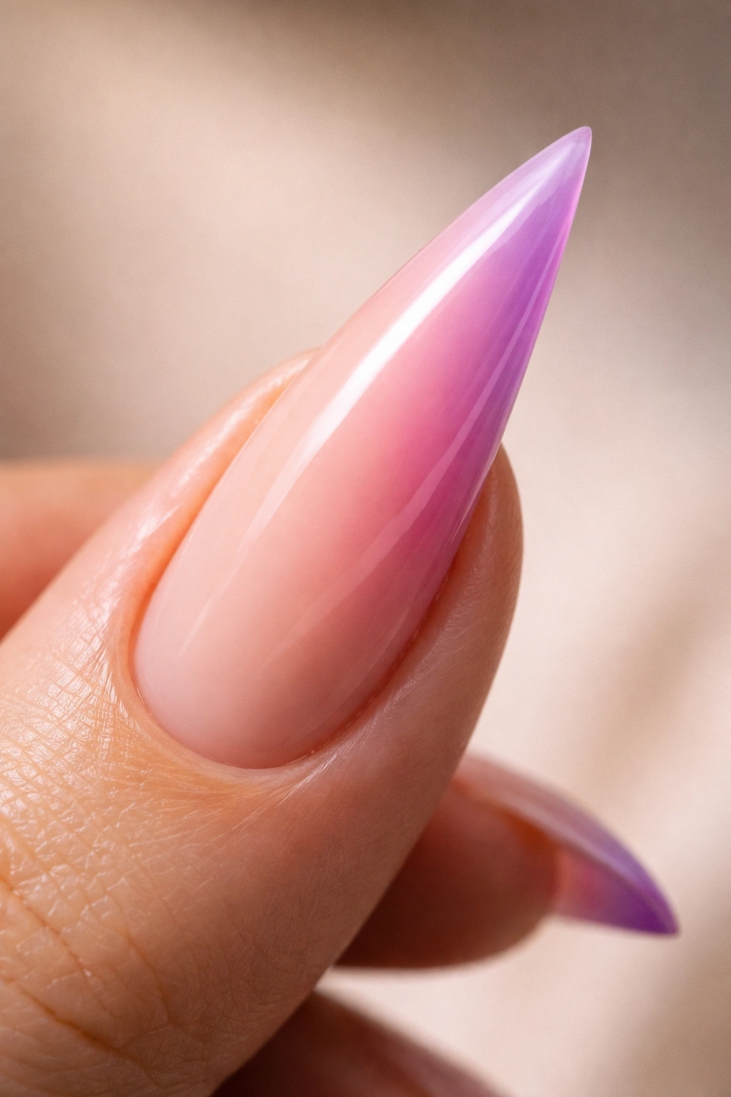 Close-up of a curved stiletto nail with an ombré gradient along the curve