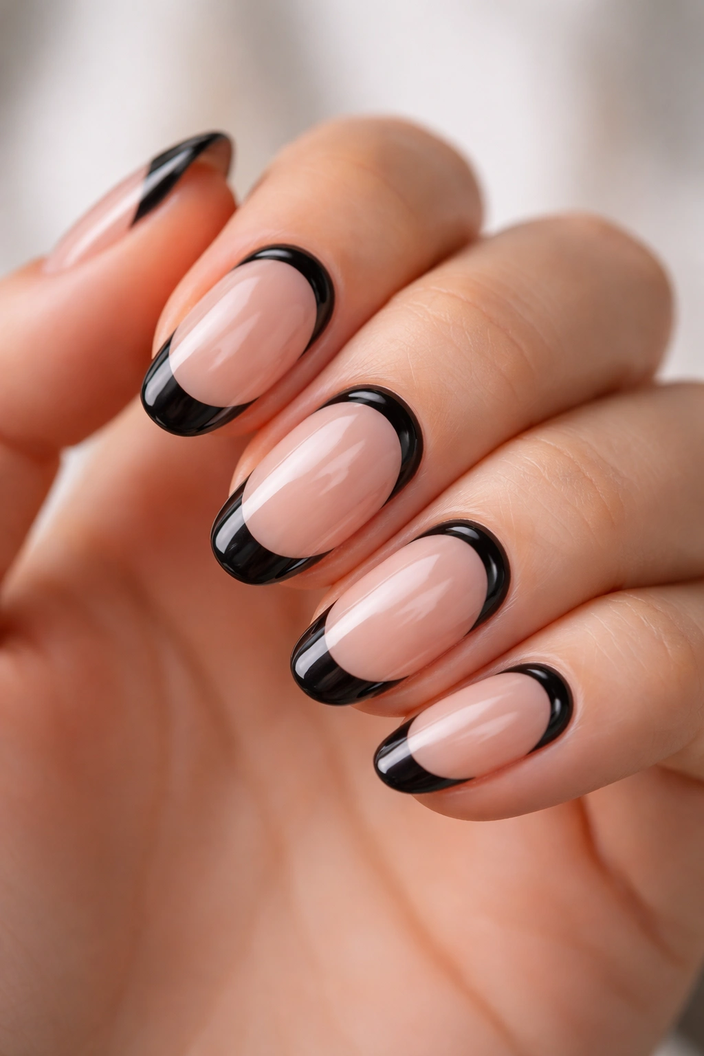 Close-up of short oval nails with a glossy black cuticle line and black tips.