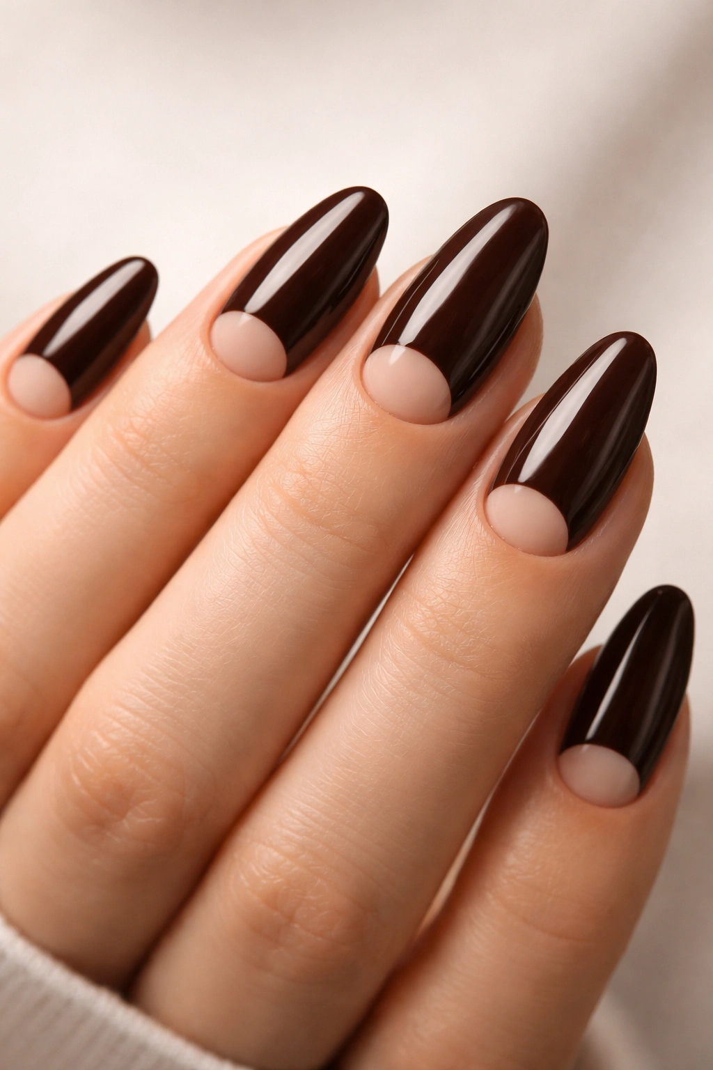 Close-up of dark brown nails with a nude half-moon at the base