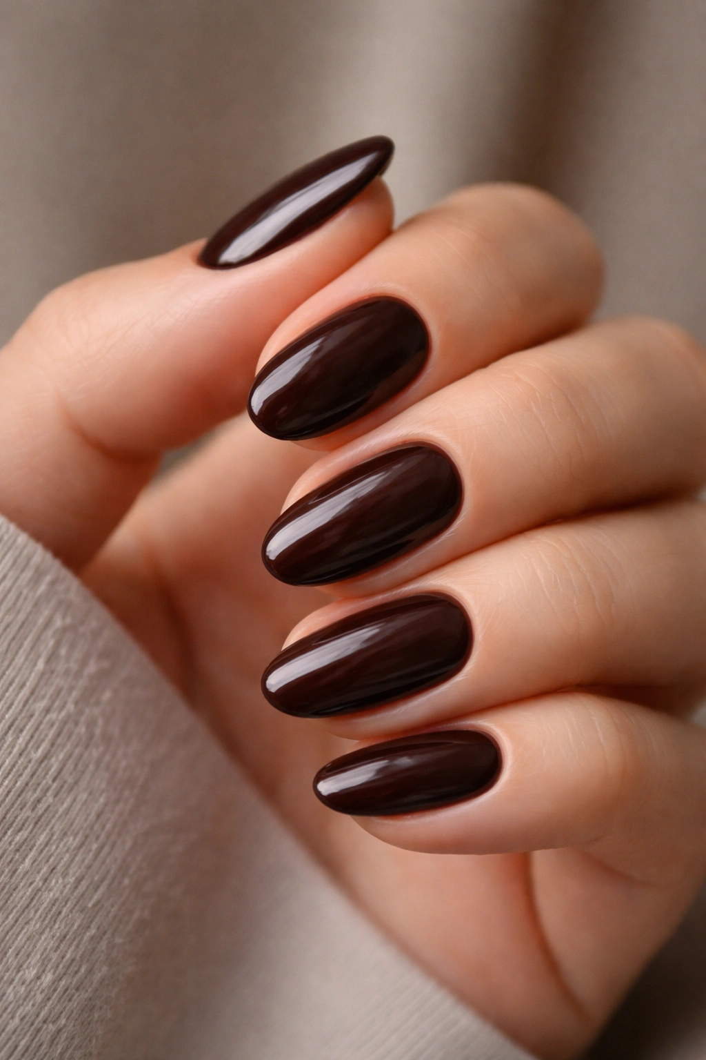 Close-up of dark chocolate almond nails on a hand with soft sheen