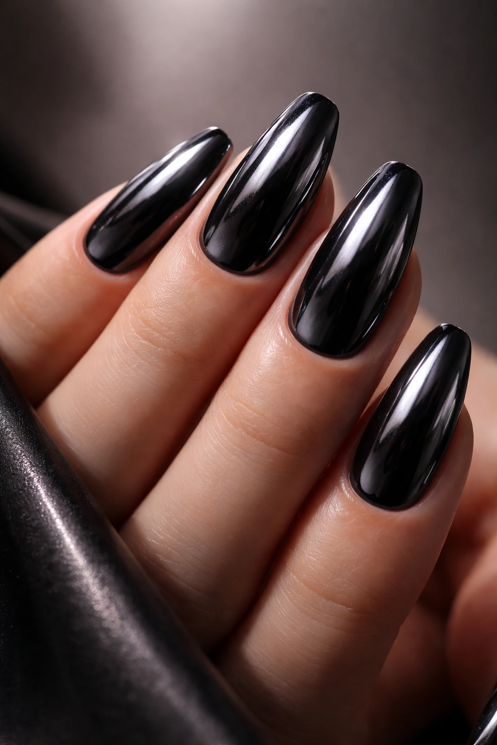 Close-up of dark chrome nails with mirror-like finish catching light