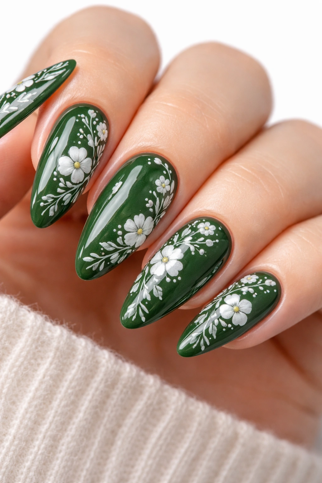 Dark green nails with white floral details on almond shape