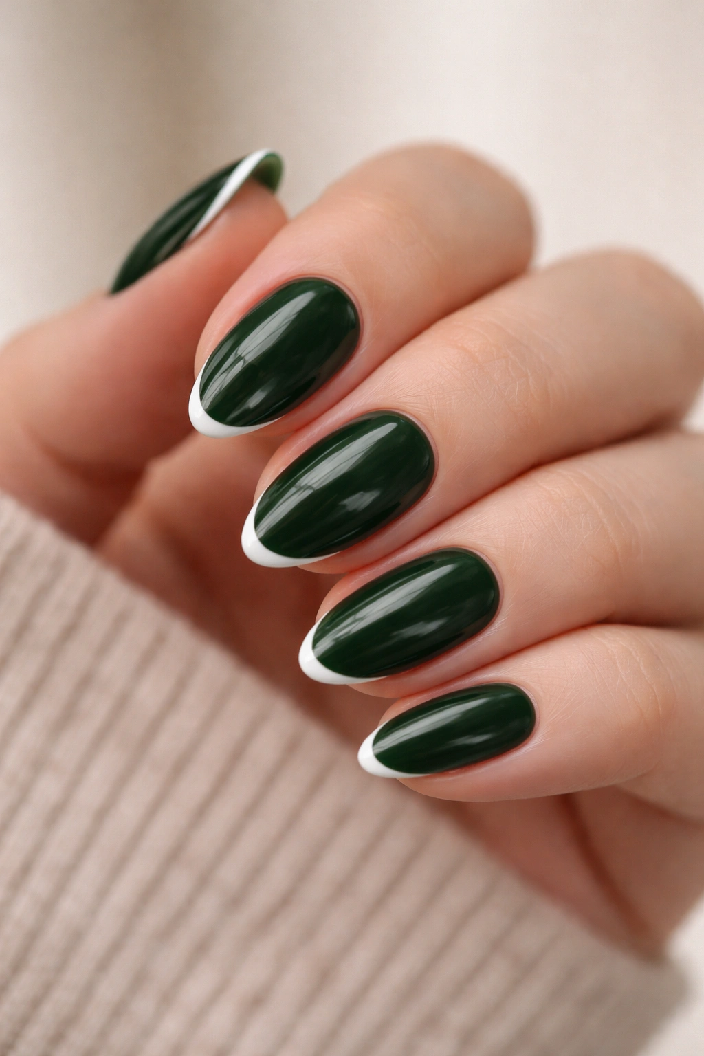 Close-up of short almond nails with dark green base and thin white micro-French edges